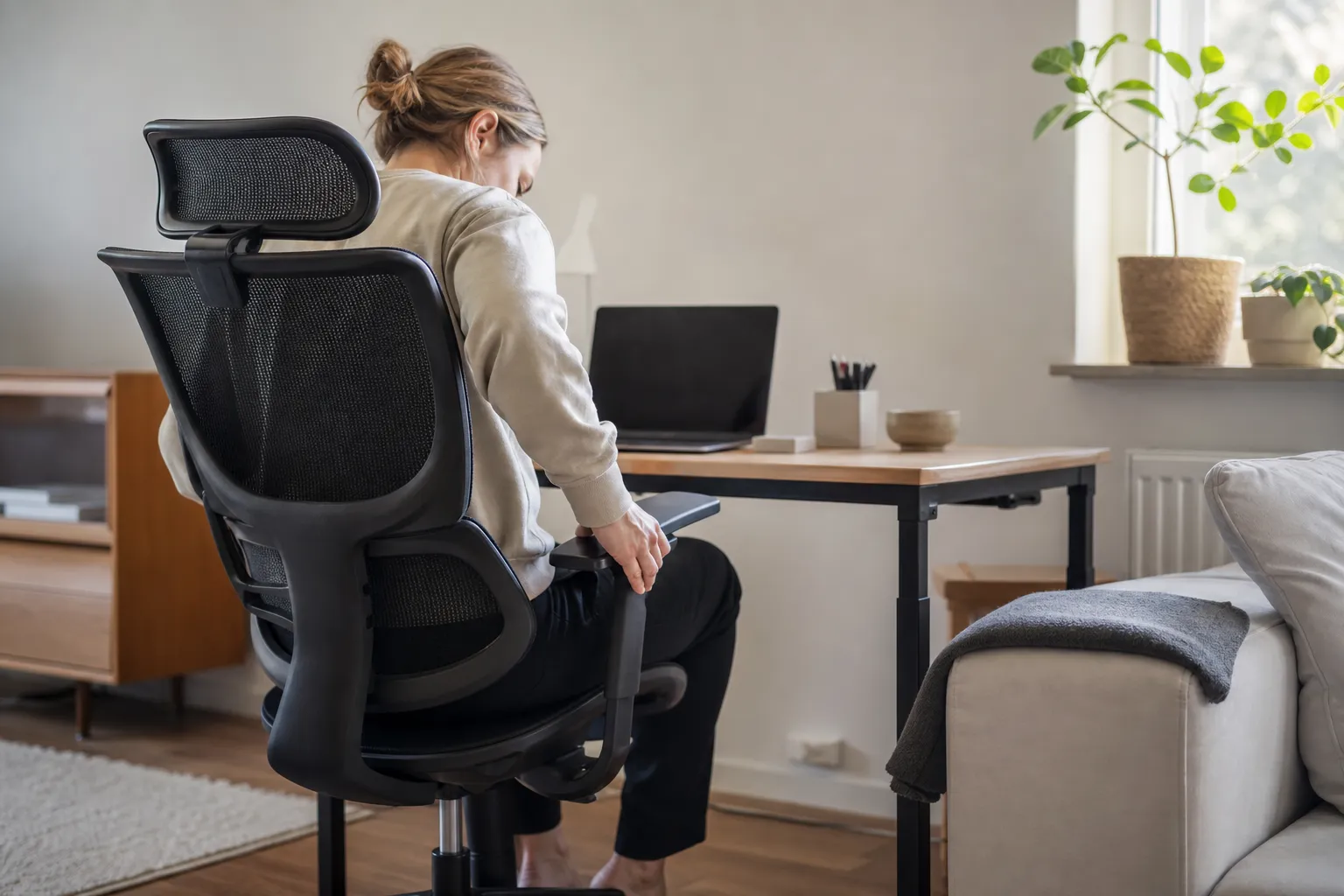 Person justerar armstödet på en ergonomisk kontorsstol vid ett hemmakontor